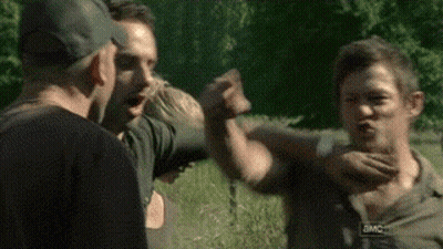A Group Of People Are Standing In A Field And One Of Them Is Holding Another Man 'S Hand . GIF