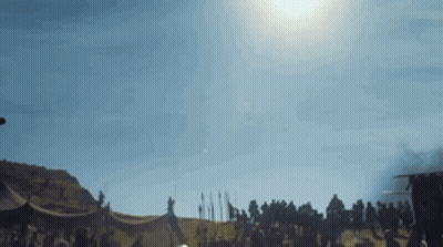 A Group Of People Are Standing In A Field With A Tent In The Background . GIF