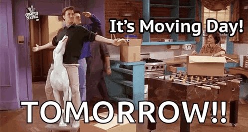 A Group Of People Are Standing In A Kitchen With Boxes And A Sign That Says It 'S Moving Day Tomorrow ! GIF