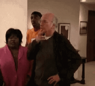 A Group Of People Are Standing In A Living Room . One Of The People Is Smoking A Cigarette . GIF