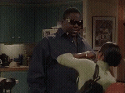 A Group Of People Are Standing In A Living Room Talking To Each Other . GIF