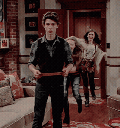 A Group Of People Are Standing In A Living Room With A Man Holding A Belt GIF