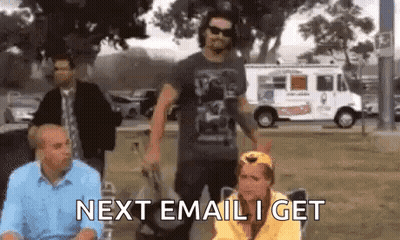 A Group Of People Are Standing In A Park And One Of Them Is Sitting In A Chair With The Words Next Email I Get . GIF