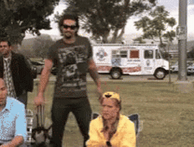 A Group Of People Are Standing In A Park In Front Of A Pizza Truck GIF
