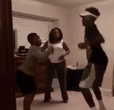 A Group Of People Are Standing In A Room And Fighting GIF