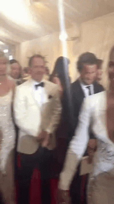 A Group Of People Are Standing In A Room And One Of Them Is Holding A Gun GIF