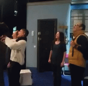 A Group Of People Are Standing In A Room Looking Up At The Sky GIF