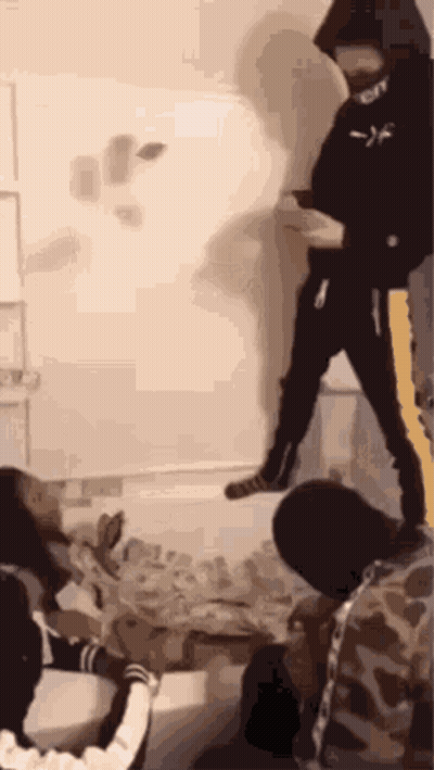 A Group Of People Are Standing In A Room With A Man In A Black Hoodie Standing In The Middle Of The Room . GIF