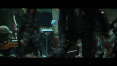 A Group Of People Are Standing In A Room With A Man Wearing A Green Suit GIF