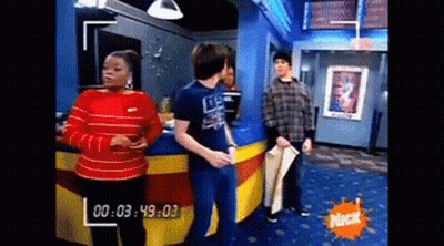 A Group Of People Are Standing In A Room With A Nick Logo On The Wall . GIF
