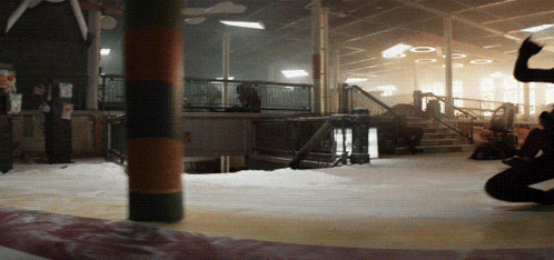 A Group Of People Are Standing In A Room With A Pillar In The Middle GIF