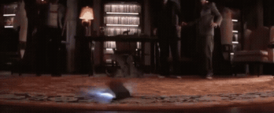 A Group Of People Are Standing In A Room With A Projector On The Floor . GIF