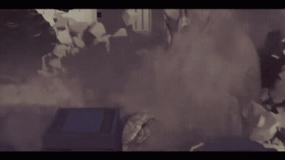 A Group Of People Are Standing In A Room With Smoke Coming Out Of The Walls . GIF