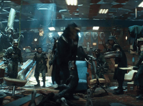 A Group Of People Are Standing In A Room With The Letter S On The Ceiling GIF
