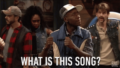 A Group Of People Are Standing In A Room With The Words What Is This Song GIF