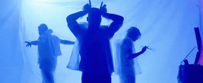 A Group Of People Are Standing In Front Of A Blue Background . GIF
