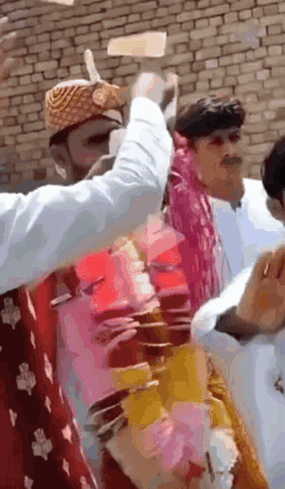 A Group Of People Are Standing In Front Of A Brick Wall And One Of Them Is Wearing A Turban GIF