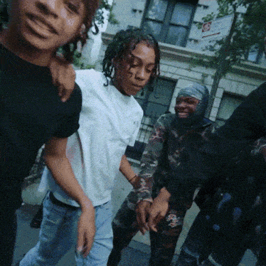 A Group Of People Are Standing In Front Of A Building With A No Smoking Sign GIF