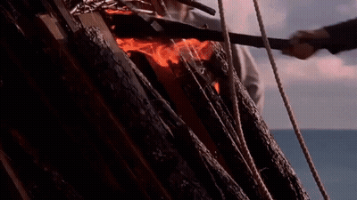 A Group Of People Are Standing In Front Of A Burning Statue Of A Man GIF
