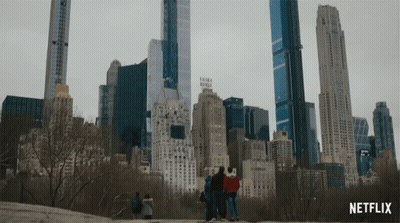 A Group Of People Are Standing In Front Of A City Skyline With A Netflix Logo In The Corner GIF