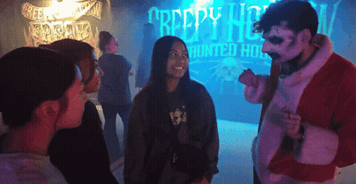 A Group Of People Are Standing In Front Of A Creepy House Sign GIF
