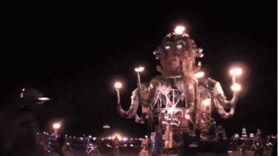 A Group Of People Are Standing In Front Of A Giant Statue Holding A Torch . GIF