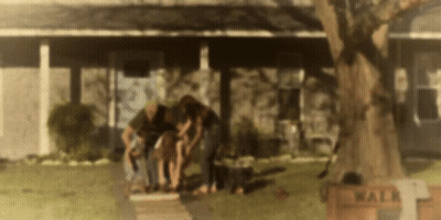 A Group Of People Are Standing In Front Of A House With A Sign That Says Walk On It . GIF