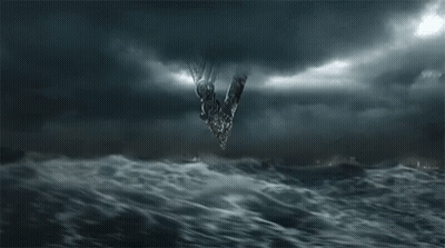 A Group Of People Are Standing In Front Of A Large Wave In The Ocean At Night . GIF