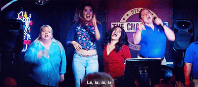 A Group Of People Are Standing In Front Of A Microphone Singing La La La La . GIF