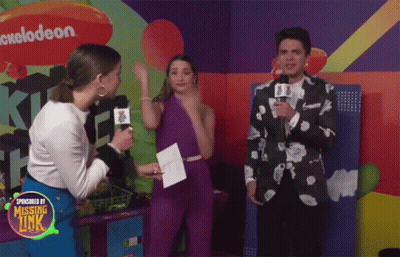A Group Of People Are Standing In Front Of A Nickelodeon Logo GIF