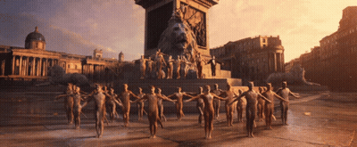 A Group Of People Are Standing In Front Of A Statue Of A Lion GIF
