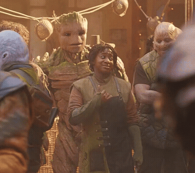 A Group Of People Are Standing In Front Of A Statue Of A Tree GIF