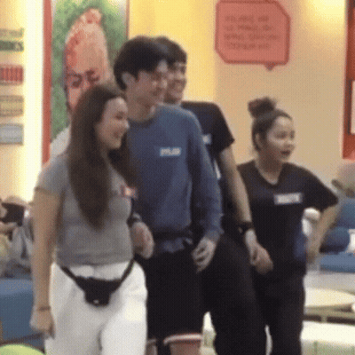 A Group Of People Are Standing In Front Of A Wall With A Sign That Says ' We Are On ' GIF