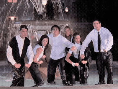 A Group Of People Are Standing In Front Of A Water Fountain GIF