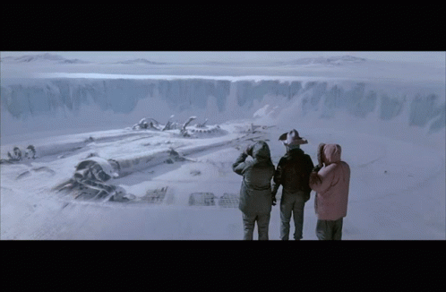 A Group Of People Are Standing In The Snow Looking At A Shipwreck GIF
