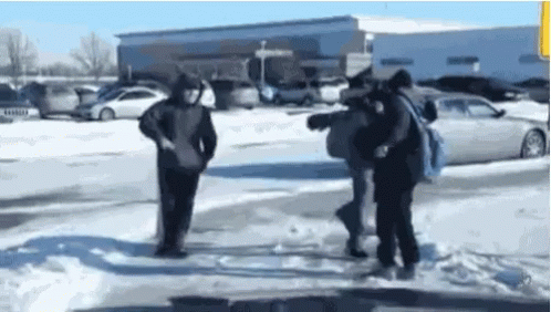 A Group Of People Are Standing In The Snow Near A Parking Lot . GIF