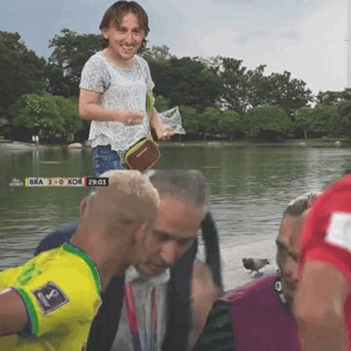 A Group Of People Are Standing Next To A Body Of Water With A Scoreboard That Says Bra 3 0 Koe GIF