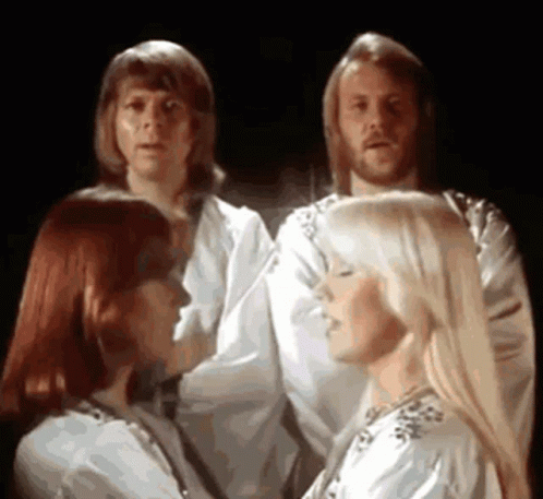 A Group Of People Are Standing Next To Each Other In A Dark Room And Singing . GIF