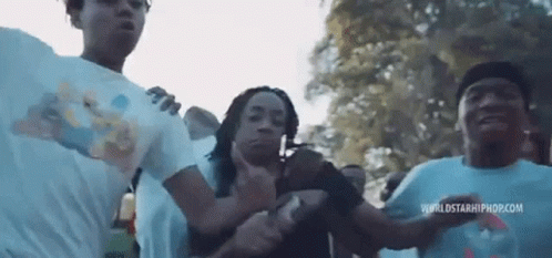 A Group Of People Are Standing Next To Each Other In A Park And Dancing . GIF