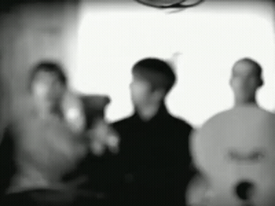 A Group Of People Are Standing Next To Each Other In A Room In A Black And White Photo . GIF