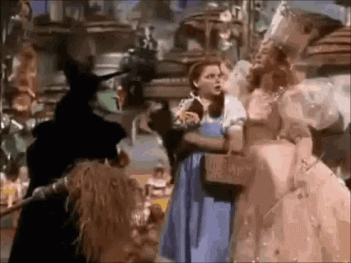 A Group Of People Are Standing Next To Each Other In A Room In A Wizard Of Oz Movie . GIF