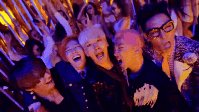 A Group Of People Are Standing Next To Each Other In A Room Laughing . GIF