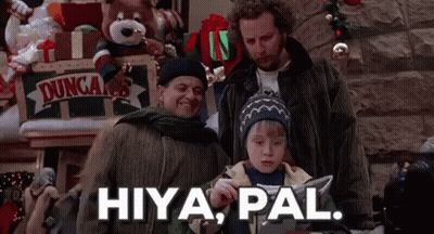 A Group Of People Are Standing Next To Each Other In A Room With Christmas Decorations . GIF