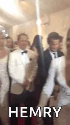 A Group Of People Are Standing Next To Each Other In A Room With The Word Hemry On The Bottom . GIF