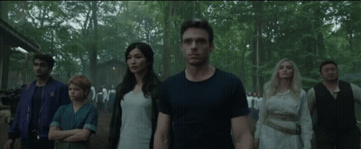 A Group Of People Are Standing Next To Each Other In The Woods GIF