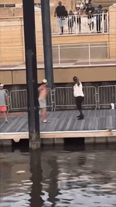 A Group Of People Are Standing On A Pier Overlooking The Water GIF