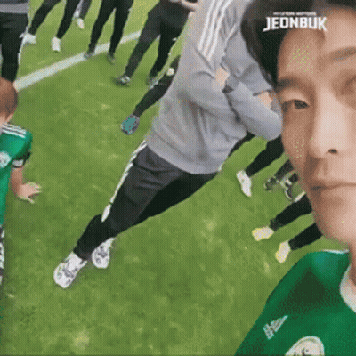 A Group Of People Are Standing On A Soccer Field And One Of Them Has The Word Jeonbuk On His Head . GIF