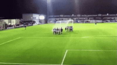 A Group Of People Are Standing On A Soccer Field At Night . GIF