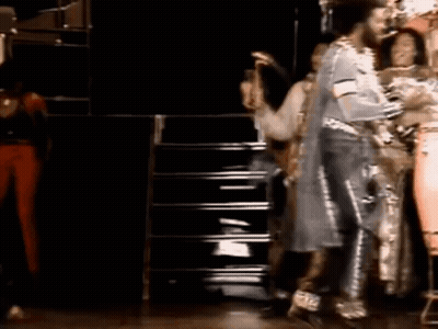 A Group Of People Are Standing On A Stage And Dancing . GIF