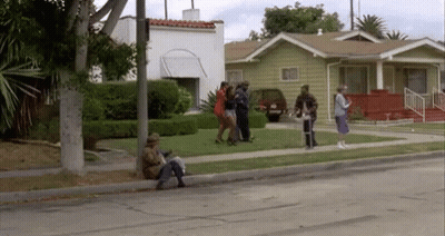 A Group Of People Are Standing On The Side Of A Street In Front Of A House . GIF
